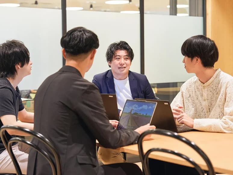 パソコンを開いて会話をする男性達